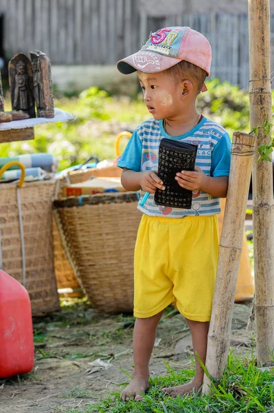 Inle Lake, Myanmar - 30 Ağustos 2016: Tanımlanamayan Birmanyalı küçük çocuk cüzdanla oynuyor. Myanma halkının yüzde 68'i Bamar etnik grubuna mensandı