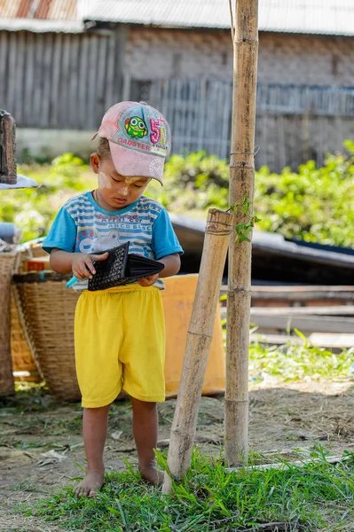 Inle Lake, Myanmar - 30 Ağustos 2016: Tanımlanamayan Birmanyalı küçük çocuk cüzdanla oynuyor. Myanma halkının yüzde 68'i Bamar etnik grubuna mensandı