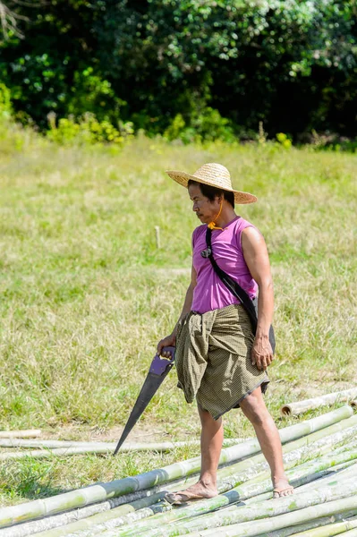 Inle Lake, Myanmar - 30 Ağustos 2016: Kimliği belirsiz Birmanyalı adam testereyle yürüyor. Myanma halkının yüzde 68'i Bamar etnik grubuna mensandı
