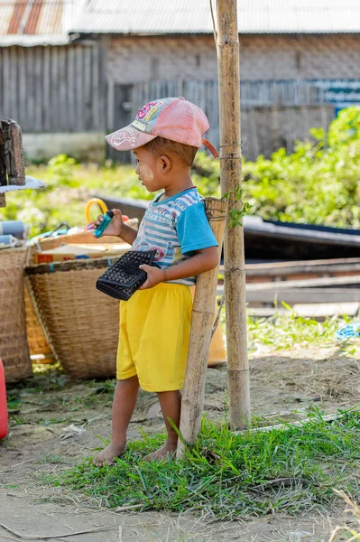 Inle Lake, Myanmar - 30 Ağustos 2016: Tanımlanamayan Birmanyalı küçük çocuk cüzdanla oynuyor. Myanma halkının yüzde 68'i Bamar etnik grubuna mensandı