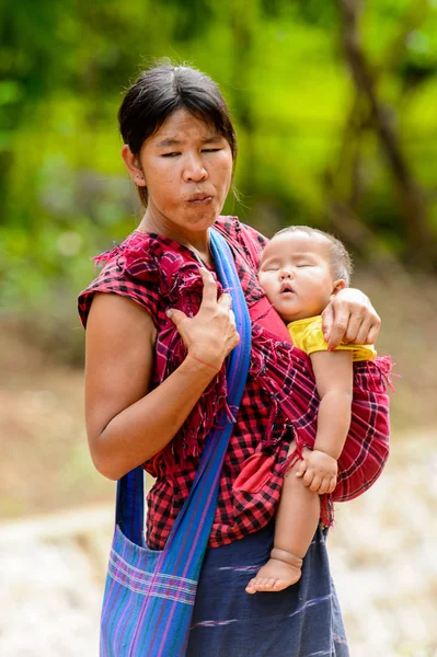 Inle Lake, Myanmar - 30 Ağustos 2016: Kimliği belirsiz Birmanyalı kadın küçük bebeğini taşıyor. Myanma halkının yüzde 68'i Bamar etnik grubuna mensandı