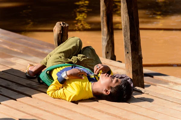 Inle Lake, Myanmar - 30 Ağustos 2016: Tanımlanamayan Birmanyalı çocuk iskelede uyuyor. Myanma halkının yüzde 68'i Bamar etnik grubuna mensandı