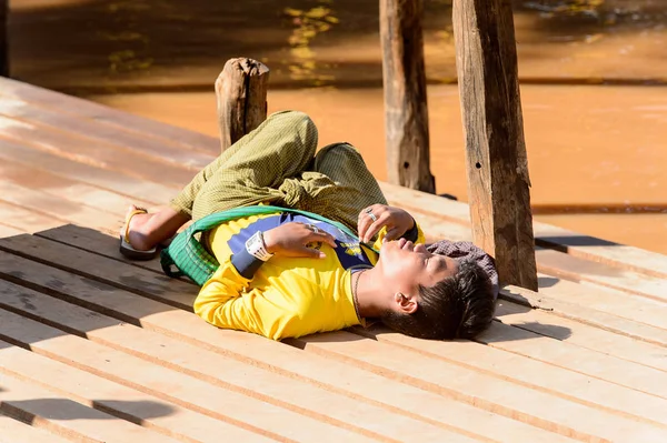 Inle Lake, Myanmar - 30 Ağustos 2016: Tanımlanamayan Birmanyalı çocuk iskelede uyuyor. Myanma halkının yüzde 68'i Bamar etnik grubuna mensandı