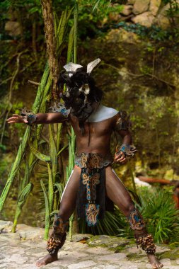 Xcaret, Meksika - Kas 8, 2015: Kimliği belirsiz bir adam bir Maya hint bir kostüm giyer ve saldırı konumunu alır. Maya, Mezoamerika'nın yerli halkından oluşan bir gruptur.
