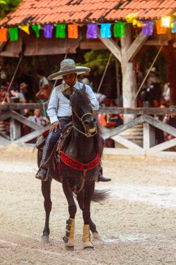 Xcaret, Meksika - 7 Kasım 2016: Kimliği belirsiz Meksikalı kovboy ata biniyor ve Xcaret parkında numaralar gösteriyor, Mexioc