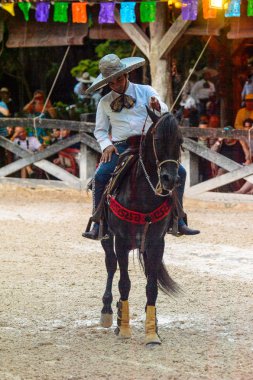 Xcaret, Meksika - 7 Kasım 2016: Kimliği belirsiz Meksikalı kovboy ata biniyor ve Xcaret parkında numaralar gösteriyor, Mexioc
