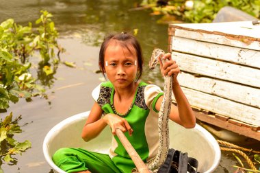 Lake Tonle Sap, Combodia - 28 Eylül 2014: Tanımlanamayan Vietnamlı kız, Güneydoğu Asya'nın en büyük tatlı su gölü olan Tonle Sap Gölü'nde leğen kemiğinde bir yılanla yelken açar.
