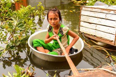 Lake Tonle Sap, Combodia - 28 Eylül 2014: Tanımlanamayan Vietnamlı kız, Güneydoğu Asya'nın en büyük tatlı su gölü olan Tonle Sap Gölü'nde leğen kemiğinde bir yılanla yelken açar.