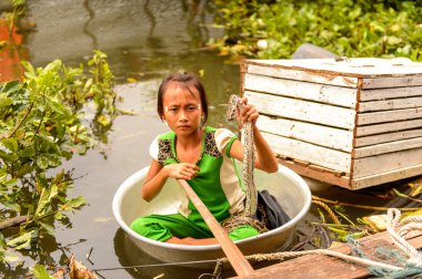Lake Tonle Sap, Combodia - 28 Eylül 2014: Tanımlanamayan Vietnamlı kız, Güneydoğu Asya'nın en büyük tatlı su gölü olan Tonle Sap Gölü'nde leğen kemiğinde bir yılanla yelken açar.