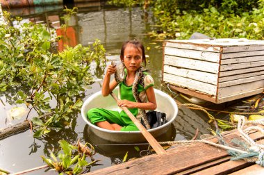 Lake Tonle Sap, Combodia - 28 Eylül 2014: Tanımlanamayan Vietnamlı kız, Güneydoğu Asya'nın en büyük tatlı su gölü olan Tonle Sap Gölü'nde leğen kemiğinde bir yılanla yelken açar.