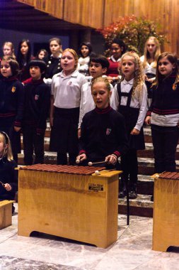 Lugano, İsviçre - 6 Aralık 2015: Kimliği belirsiz çocuklar kilisede bir Noel şarkısı söylüyor. Bilinen ilk Noel ilahileri dördüncü yüzyıl Roma'sında ortaya çıktı