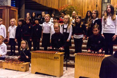 Lugano, İsviçre - 6 Aralık 2015: Kimliği belirsiz çocuklar kilisede bir Noel şarkısı söylüyor. Bilinen ilk Noel ilahileri dördüncü yüzyıl Roma'sında ortaya çıktı