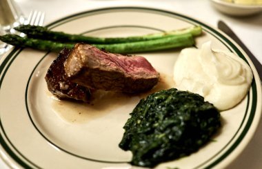 Bir tabak kuru yaşlı fileto mignon ile kuşkonmamış ve bir DAB kremalı ıspanak ve patates püresi.