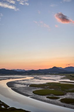 Pembe bir bulut ve Güney Kore 'deki Sunchoenman Körfezi Wetland Rezervi' nde bir nehir..