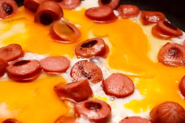 Kızarmış yumurta sosis ile bir tencerede kızartılır