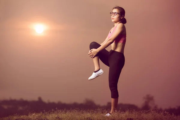 woman exercise with sunset, asian woman  stretching muscle before exercise, smart healthy person warm up or cool down before exercise or after exercise, knee to chest and  standing on one leg