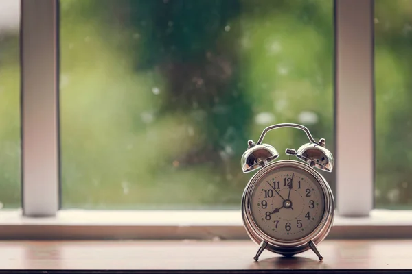 alarm clock on wooden table and glass window, working time of alrm clock