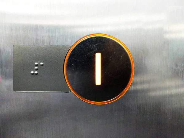 orange light of number one of lift and close up braille, a form of written language for blind people by respond from dots contact, first floor of lift working