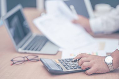 Elde kalem tutan iş adamı hesap makinesi üzerinde çalışıyor 