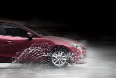 Sel sularında giden araba hareket bulanıklığı çekiyor. Hareket eden araba yağmuru Tekerleklerden fışkıran su birikintisi