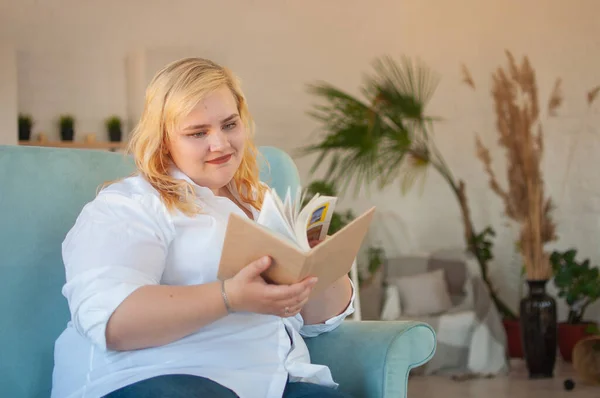 Молодая женщина с избыточным весом читает бумажные книги, отдыхает в одиночестве, развивает себя — стоковое фото