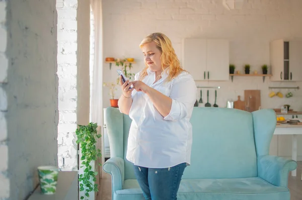 Young beautiful overweight woman makes online order in living room at home — Stock Photo, Image