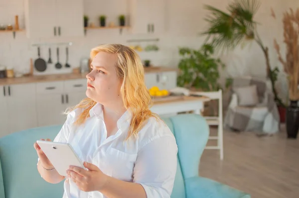 Young beautiful overweight woman makes online order in living room at home — Stock Photo, Image