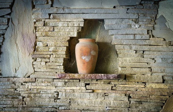 Oude handgemaakte klei wijnkan met spinnenweb staande op een stenen raam in het midden van stenen muur. decoratie en ambacht voor achtergrond Stockafbeelding