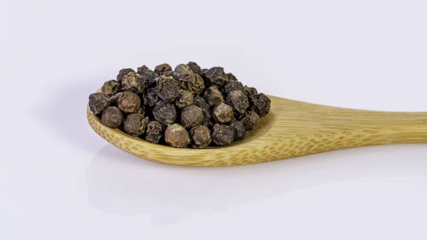 Black pepper corns on bamboo spoon isolated on white background — Stock Photo, Image