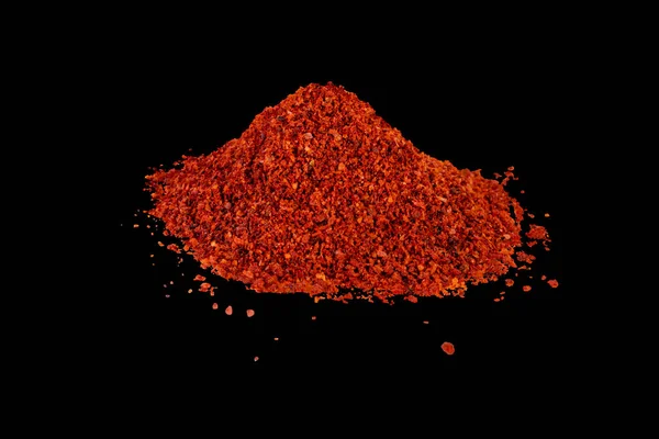 Heap of dried crushed hot red pepper on isolated black — Stock Photo, Image