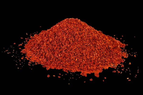 Heap of dried crushed hot red pepper on isolated black — Stock Photo, Image
