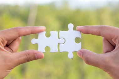 İki elle parçalı bulmaca parça bağlayıcılar, yeşil bokeh arka plan, ortak iş kavramları