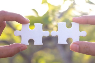 İki elle parçalı bulmaca parça bağlayıcılar, doğal yeşil arka plan, ortak iş kavramları