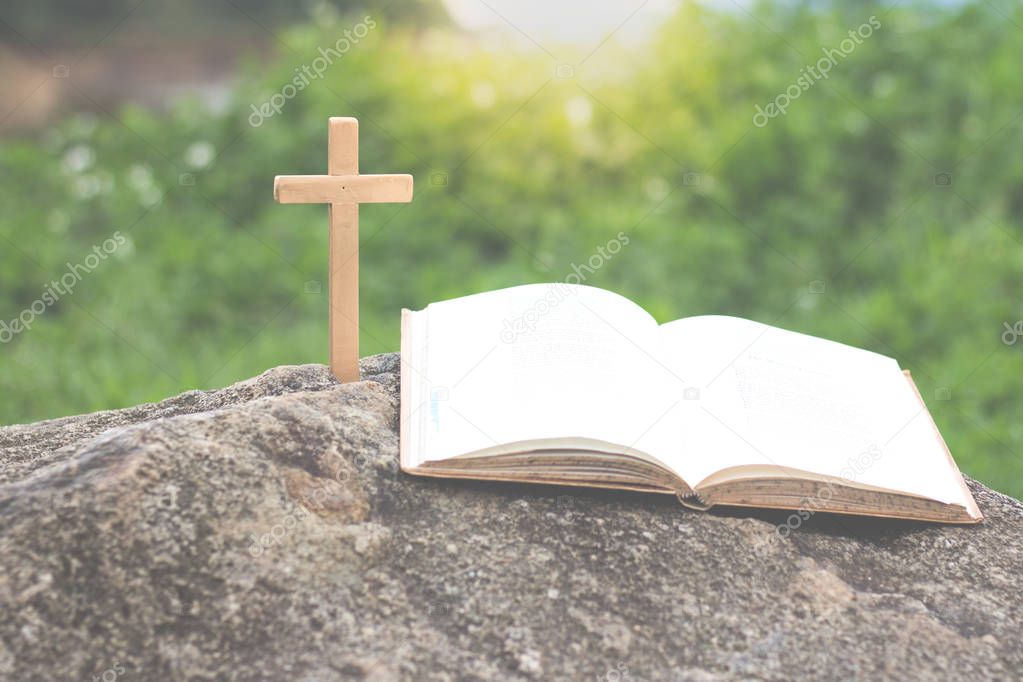 The cross and the bible is on the rock,Green background, Worship, sins and prayer.