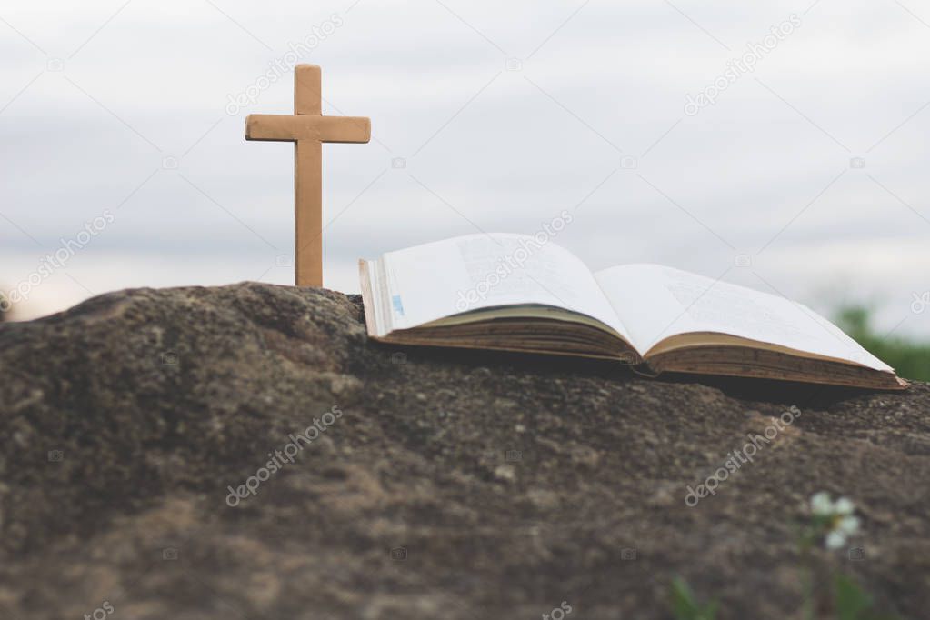 The cross and the bible is on the rock.Worship, sins and prayer.