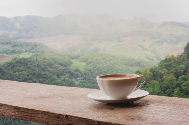 A cup of coffee on the table and a beautiful mountain background. clipart
