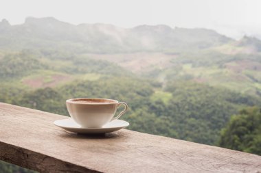 Bir fincan kahve tablo ve güzel dağ arka plan.