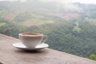 Bir fincan kahve tablo ve güzel dağ arka plan.