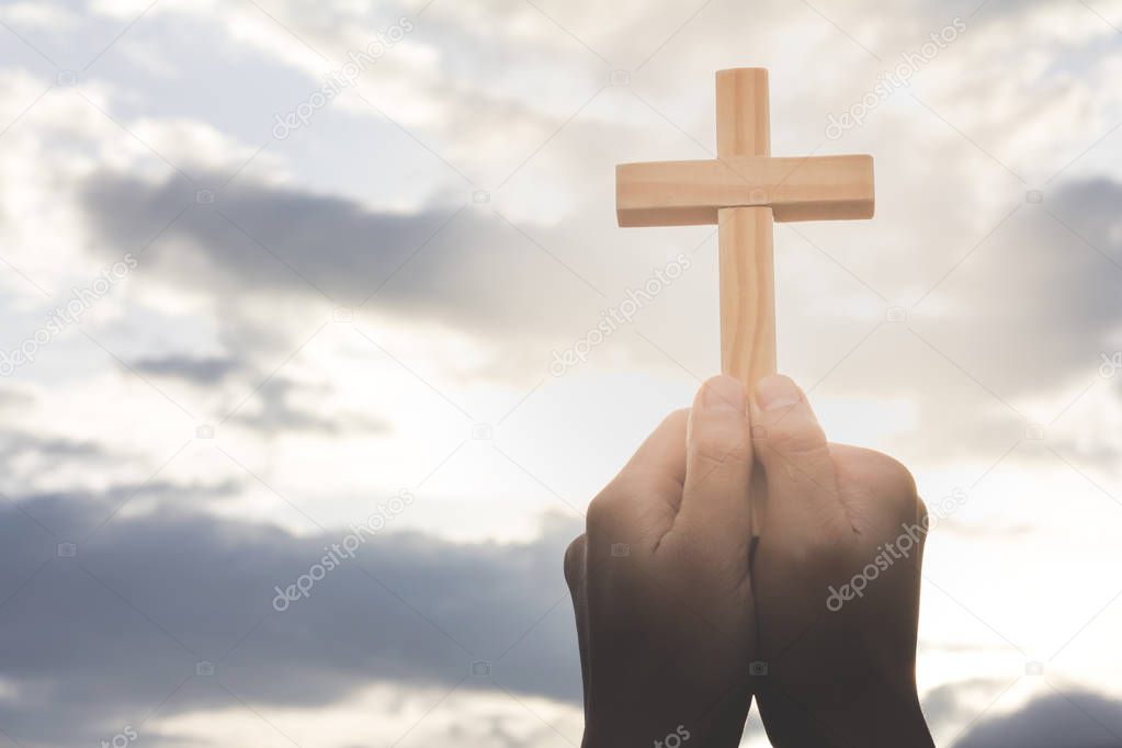 Human hand holding a cross, the background is the sunrise., Concept for Christian, Christianity, Catholic religion, divine, heavenly, celestial or god.