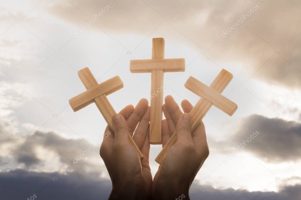 Human hand holding three cross, the background is the sunrise., Concept for Christian, Christianity, Catholic religion, divine, heavenly, celestial or god.