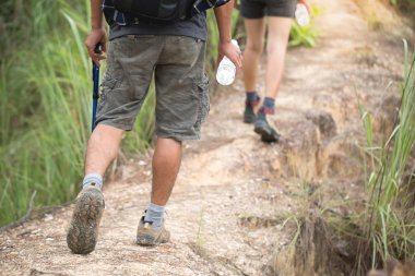 Bir kadın ve bir adam bir yol bir dağ ormanda yürüyor. Arkadan görüntüleyin. Spor ayakkabı yakın çekim bacaklar. Hiking ayakkabıları.