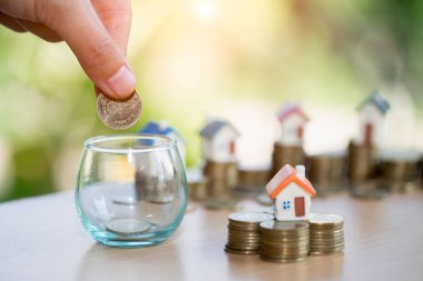 Yığın altın sikke ve ev modeli, yeni ev ve Yatırım Emlak konsepti ile satın almak için para tasarrufu tutan bir erkek el.
