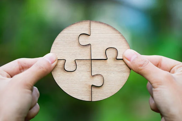 Closeup hand of connecting jigsaw puzzle to complete the mission with sunlight effect, Business solutions, success and strategy concept