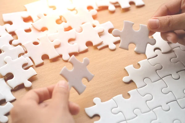 Closeup hand of connecting jigsaw puzzle to complete the mission with sunlight effect, Business solutions, success and strategy concept