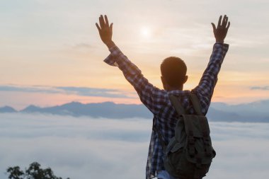 Turist ile dağ yamacında sırt çantası ile üzerine ellerini kaldırdı, vadi sis ile kaplıdır ve güzel gün doğumu vardır. Güzellik, Doğa, turizm ve seyahat kavramı.
