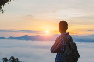 Turist ile dağ yamacında sırt çantası ile üzerine ellerini kaldırdı, vadi sis ile kaplıdır ve güzel gün doğumu vardır. Güzellik, Doğa, turizm ve seyahat kavramı.