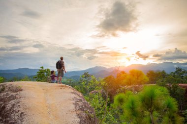  tepenin üstünde duran ve vadi üzerinde gün doğumu zevk yürüyüşçüler