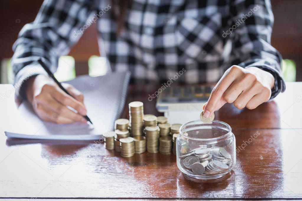 Business accounting with saving money with hand putting coins in jug glass, Businessman Writing Financial Accounting, concept financial
