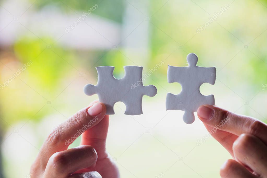 Closeup hand of connecting jigsaw puzzle to complete the mission with sunlight effect, Business solutions, success and strategy concept