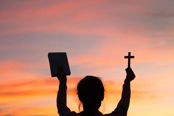 Silueta Manos Mujer Joven Sosteniendo Sagrada Biblia Levantando Cruz Cristiana — Foto de Stock